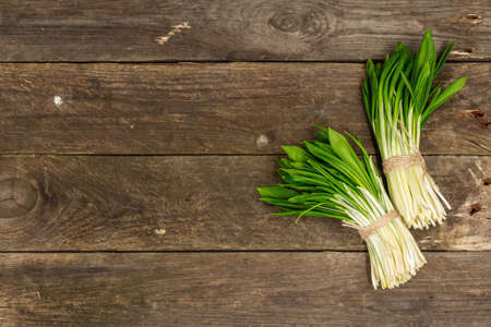 Bunches of a fresh harvest of spring ramson or wild leek. Fragrant spicy leaves on vintage wooden table background, hard light, dark shadow, top viewの写真素材