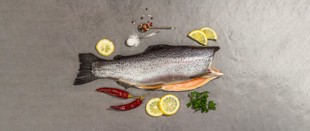 Raw trout carcass with spices and herbs on a gray stone concrete background. Sea fish, healthy food,...