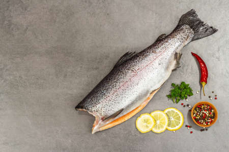 Raw trout carcass with spices and herbs on a gray stone concrete background. Sea fish, healthy food, top viewの写真素材