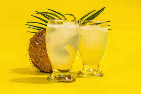 Refreshing summer Coconut martini. Non-alcoholic Margarita cocktail, trendy hard light, dark shadow.Bright yellow background, close upの写真素材