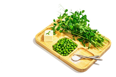 Set of fresh spring foods - young pea, its sprouts, butter and sea salt. Serving board isolated on...