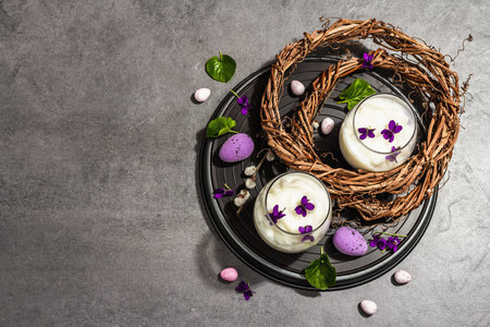 Happy Easter festive composition. Vegan panna cotta dessert with fresh violet flower. Striped very...