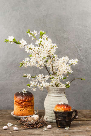 Traditional Easter cake in a rustic style. Vintage baking pot, blooming cherry plum branches. Old wooden background, greeting cardの写真素材