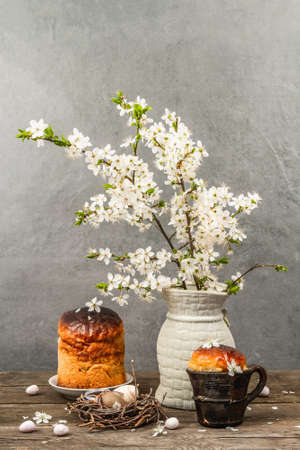 Traditional Easter cake in a rustic style. Vintage baking pot, blooming cherry plum branches. Old wooden background, greeting cardの写真素材