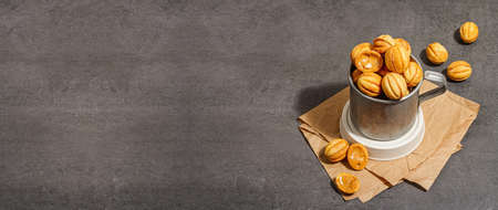 Cookies in the shape of walnuts with condensed milk cream filling. Delicious shortbread sandwiches, modern vegan baking. Stone concrete background, banner formatの写真素材