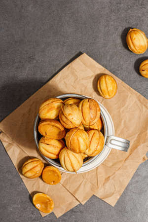 Cookies in the shape of walnuts with condensed milk cream filling. Delicious shortbread sandwiches, modern vegan baking. Stone concrete background, top viewの写真素材