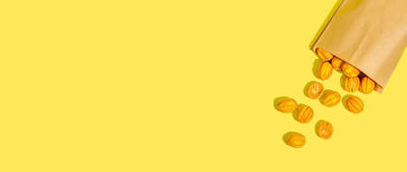 Cookies in the shape of walnuts with condensed milk cream filling. Delicious shortbread sandwiches, modern vegan baking. Trendy hard light, dark shadow, yellow background, banner formatの写真素材