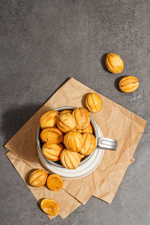 Cookies in the shape of walnuts with condensed milk cream filling. Delicious shortbread sandwiches, modern vegan baking. Stone concrete background, top viewの写真素材