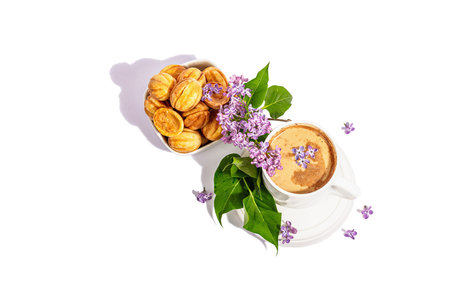 Cup of coffee and cookies in the shape of walnuts with cream filling isolated on a white background....