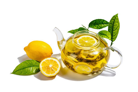 Lemon tea with ripe fruits and fresh leaves isolated on white background. Hot beverage in a glass teapot, hard light, dark shadow, flat lay, close upの写真素材