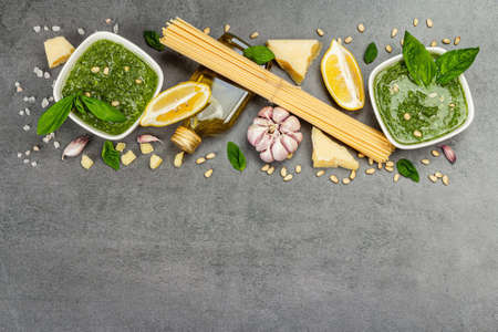 Traditional ingredients for the preparation of classic Italian pasta. Dry spaghetti, basil pesto, parmesan, lemon and garlic. Gray stone concrete background, top viewの写真素材