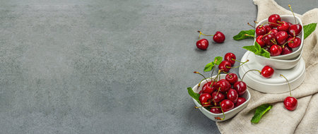 Ripe sweet cherries with fresh mint leaves, traditional summer fruits. Trendy concrete stands,...