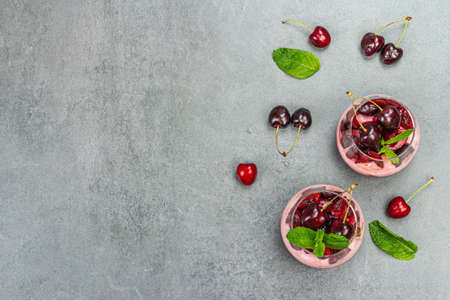 Delicious Italian dessert panna cotta with sweet cherry sauce, fresh berries and mint leaves. Stone concrete background, top viewの写真素材
