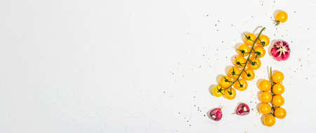 Culinary background with ripe vegetables. Yellow tomato cherries, chili pepper, garlic, purple basil. Fresh vegetables on white putty background, modern hard light, dark shadow, flat lay, top viewの写真素材