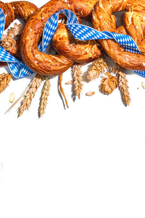 Oktoberfest concept - pretzels with traditional pattern ribbon and ears wheat isolated on white background. A trendy hard light, dark shadowの写真素材