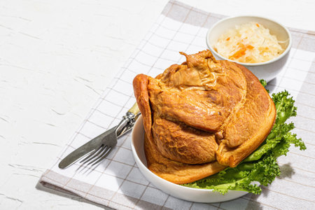 Oktoberfest smoked pork knuckle eisbein with fermented sour cabbage. Traditional German festival food. Trendy hard light, dark shadow, white plaster background, copy spaceの写真素材