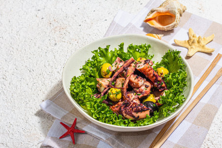 Octopus salad with lettuce, olives and spices in a bowl. Fresh and healthy seafood, marine decor. Trendy hard light, dark shadow, plaster background, copy spaceの写真素材