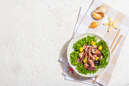 Octopus salad with lettuce, olives and spices in a bowl. Fresh and healthy seafood, marine decor. Trendy hard light, dark shadow, plaster background, top viewの写真素材