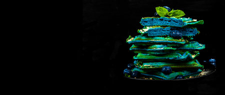 Homemade Belgium Waffles with blueberries. Gluten-free blue dessert, fresh fruits and mint. Trendy hard light, dark shadow. Black stone concrete background, banner formatの写真素材