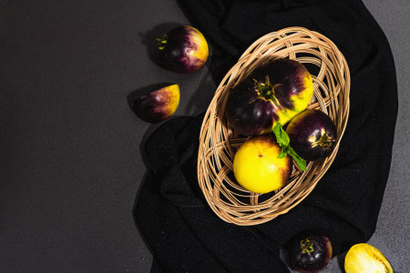 Yellow-violet Tomatoes variety Primary colors in a wicker basket. Harvest of ripe vegetables, trendy...