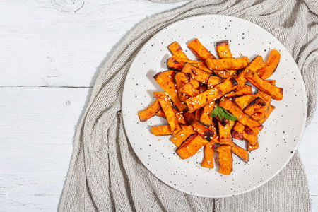 Baked organic batata fries with spices and sauce. Sweet vegetable, served portion and cutlery,...