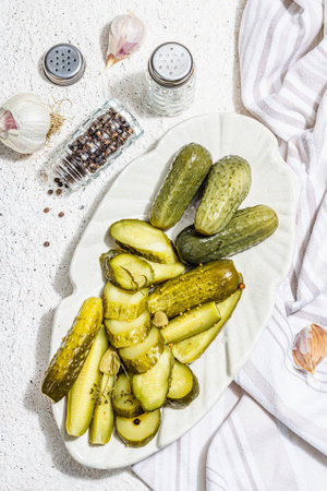 Pickled cucumbers for winter organic food. Jar of homemade gherkins, clean eating, vegan concept. Trendy hard light, dark shadow, white plaster background, top viewの写真素材