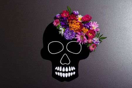 Paper human skull for Mexico's Day of the Dead (El Dia de Muertos) with traditional flowers. Trendy hard light, dark shadow. Black stone concrete background, top viewの写真素材