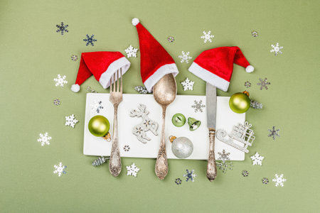 Vintage cutlery with traditional Christmas decor. New Year festive symbols, table setting, hard light, dark shadow. Trendy Savannah Green color background, flat lay, top viewの写真素材