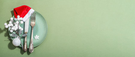 Christmas table setting with empty ceramic plates, traditional accessories on trendy Savannah Green color background. Festive New Year cutlery, hard light, dark shadow, flat lay, banner formatの写真素材