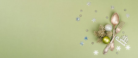 Christmas table setting with traditional accessories on trendy Savannah Green color background. Festive New Year cutlery, hard light, dark shadow, flat lay, banner formatの写真素材