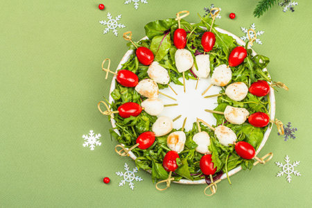 Charcuterie wreath in traditional New Year color design with Christmas decorations. Modern snack, matte green background, flat lay, top viewの写真素材