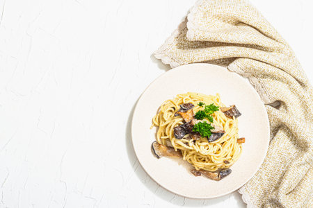 Spaghetti pasta with oyster mushrooms, creamy sauce and parsley. Healthy vegan food ready to eat. Trendy hard light, dark shadow, white background, top viewの写真素材