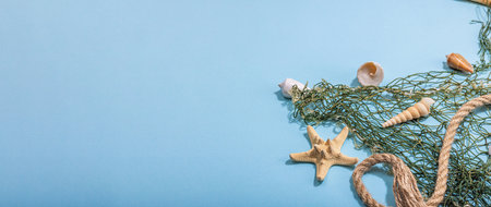 Blue nautical background with sea shells, starfishes and fishing net. Assorted marine animals, vacation concept. Trendy hard light, dark shadow, flat lay, banner formatの写真素材
