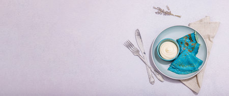 Thin blue pancakes with creamy sauce. Healthy vegan non lactose and gluten free food, breakfast concept. Trendy hard light, dark shadow, light stone concrete background, banner formatの写真素材