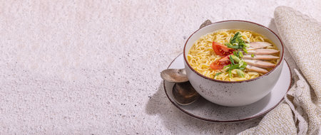 Spicy noodles with beef broth. Hot dish, cutlery, hard light, dark shadow. Stone concrete background, flat lay, banner formatの写真素材
