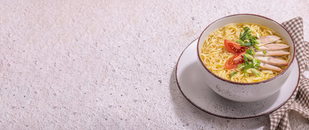 Spicy noodles with beef broth. Hot dish, cutlery, hard light, dark shadow. Stone concrete background, flat lay, banner formatの写真素材