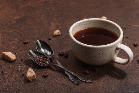 Cup of coffee in dark tones. Morning good mood, breakfast concept. Brown sugar, cutlery, hard light, dark shadow, stone concrete background, copy spaceの写真素材