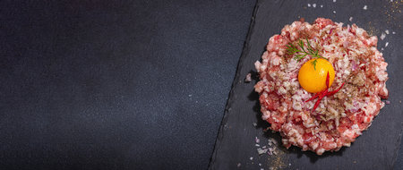 Homemade minced meat, spices and herbs. Traditional raw ingredients for cooking cutlets or meatballs. Trendy hard light, dark shadow, light stone concrete background, banner formatの写真素材