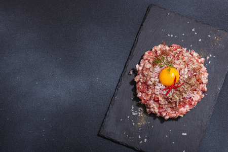 Homemade minced meat, spices and herbs. Traditional raw ingredients for cooking cutlets or meatballs. Trendy hard light, dark shadow, light stone concrete background, top viewの写真素材
