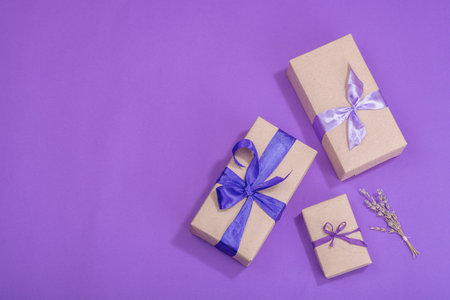 Zero waste gift concept. Wrapped in craft paper surprise box for Anniversary, Mothers or Valentines Day. Happy birthday greeting card, purple background, flat lay, top viewの写真素材