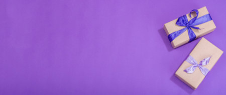 Zero waste gift concept. Wrapped in craft paper surprise box for Anniversary, Mothers or Valentines Day. Happy birthday greeting card, purple background, flat lay, banner formatの写真素材