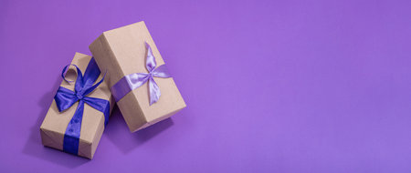 Zero waste gift concept. Wrapped in craft paper surprise box for Anniversary, Mothers or Valentines Day. Happy birthday greeting card, purple background, flat lay, banner formatの写真素材