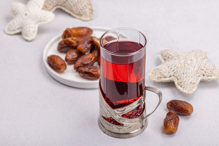 Hibiscus hot tea with dates. Traditional Ramadan Kareem concept snack for Iftar or Suhoor meal on light stone concrete background. An Arabian sweet treat, hard light, dark shadow, copy spaceの写真素材