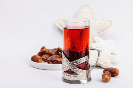 Hibiscus hot tea with dates. Traditional Ramadan Kareem concept snack for Iftar or Suhoor meal on light stone concrete background. An Arabian sweet treat, hard light, dark shadow, copy spaceの写真素材