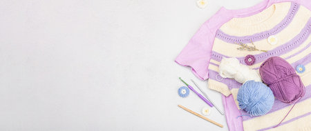 Handmade crocheted baby t-shirt in lilac tones. Stuff and props contains thread, hooks, knitting...