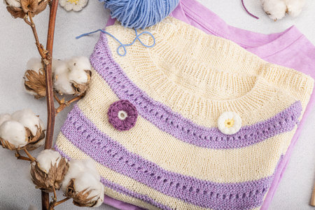 Handmade crocheted baby t-shirt in lilac tones. Stuff and props contains thread, hooks, knitting...