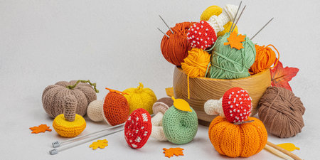 Set of clew of thread for knitting. Crocheted mushrooms, pumpkins, handmade, autumn hobby concept. Props and special craft tools on light stone concrete background, banner formatの写真素材