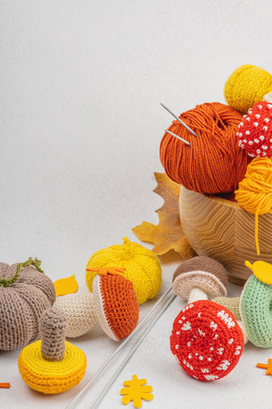 Set of clew of thread for knitting. Crocheted mushrooms, pumpkins, handmade, autumn hobby concept. Props and special craft tools on light stone concrete background, copy spaceの写真素材