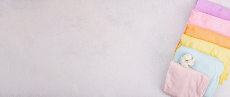 Vertical storage of clothing. Spring closet cleaning, eco friendly concept. Pastel colored baby T-shirts, folded after machine washing. Light stone concrete backgroundの写真素材