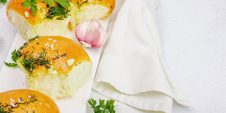 Aromatic garlic buns. Fresh baked goods, a traditional gluten-free soup snack. Parsley, spices, olive oil. Light stone concrete background, banner formatの写真素材